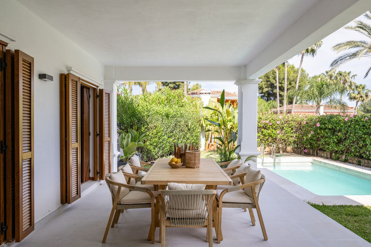Covered terrace with dining set beside the pool